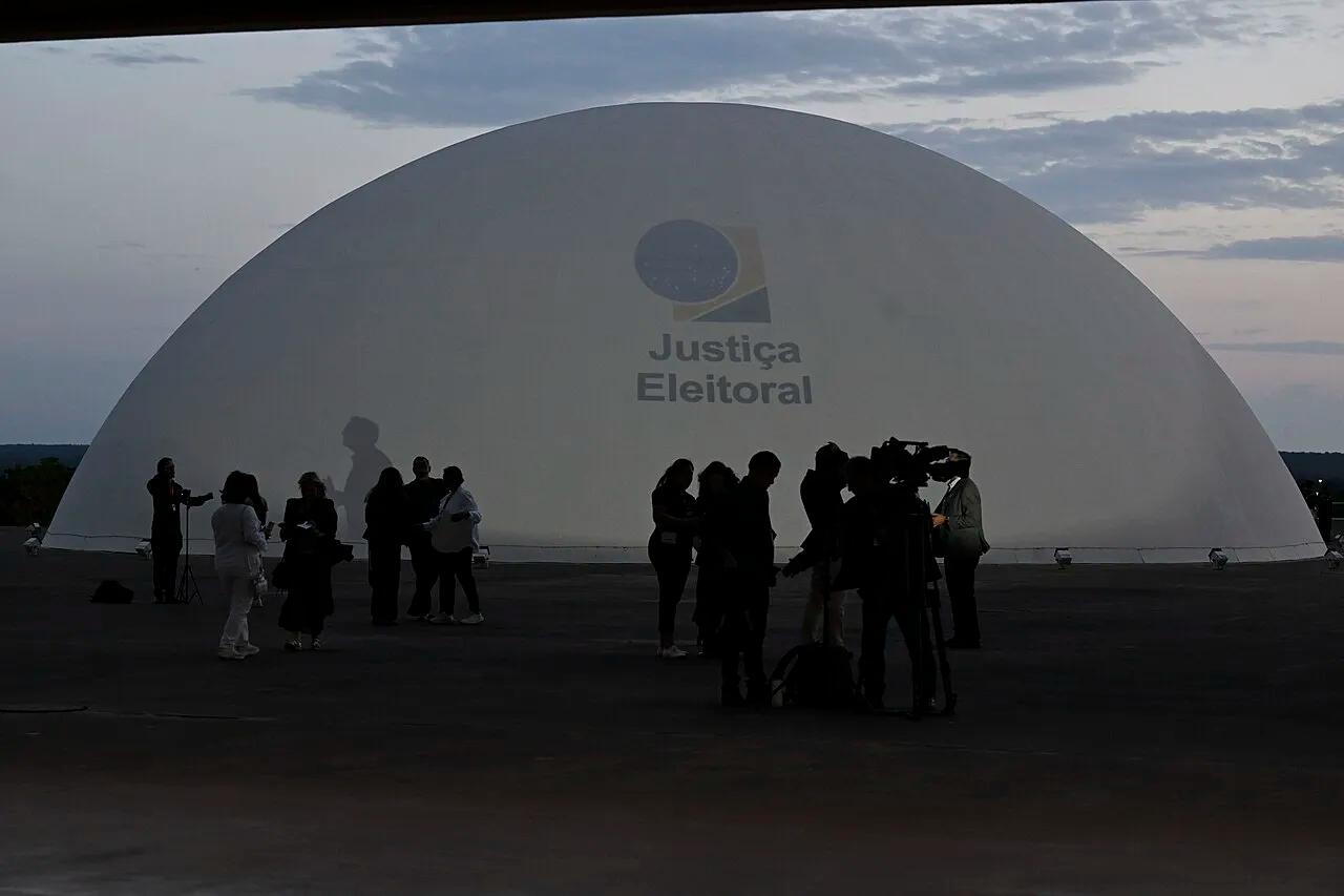 A cúpula do edifício-sede do Tribunal Superior Eleitoral, em Brasília, com a projeção do logotipo da Justiça Eleitoral na noite da apuração do primeiro turno, em 4 de outubro de 2026.
