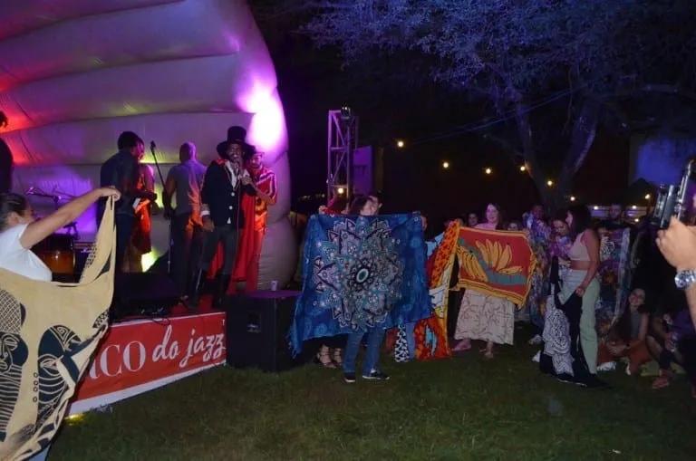 Público ergue cangas estampadas diante do palco-bolha do Buraco do Jazz: o Concurso de Cangas virou uma das marcas das edições no gramado da Praça dos Três Poderes, em Brasília.