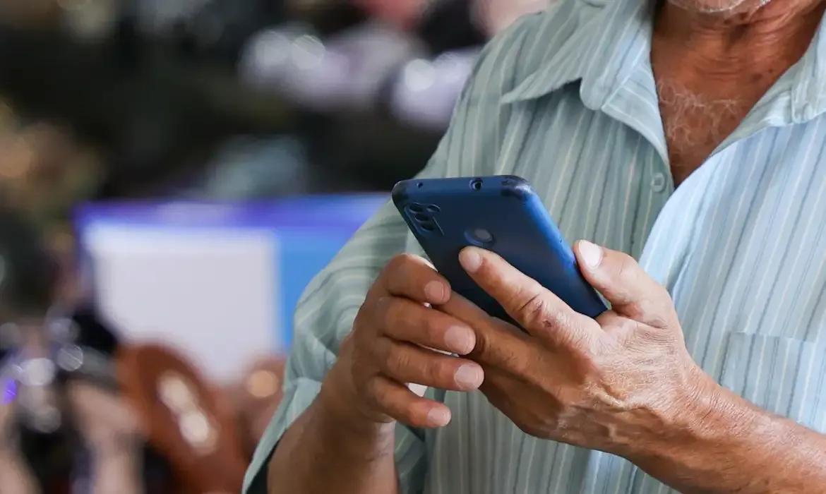 Homem usa o celular na Rodoviária do Plano Piloto, em Brasília, em agosto de 2026.